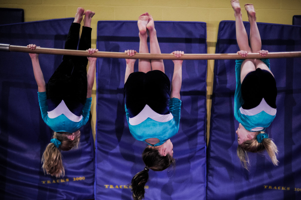 three young gymnasts see the world upside down on the bar