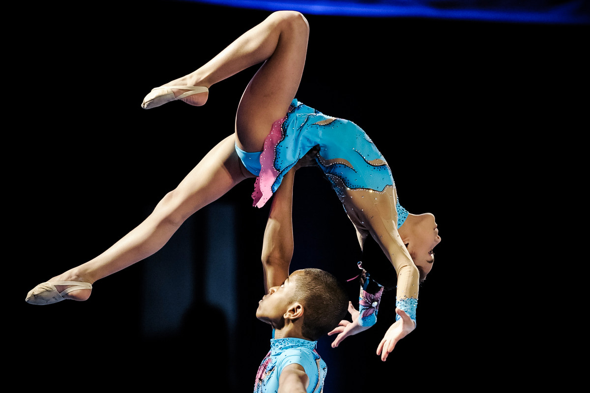 young acrobatic gymnast balances above her partner's head