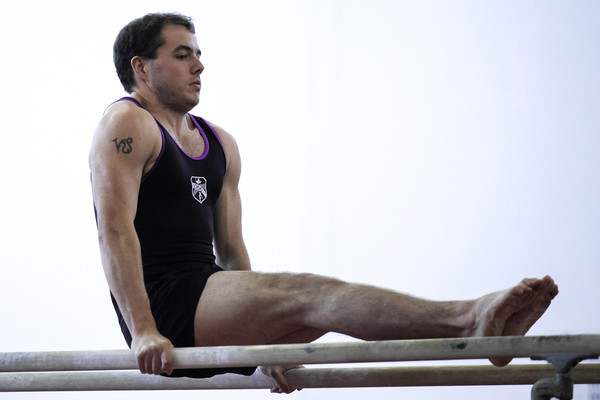 male adult gymnast takes on the parallel bars