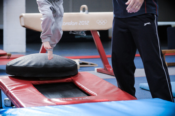 budding gymnast takes a leap supported by his coach
