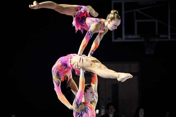 Trio of acrobatic gymnasts trio performing at competition